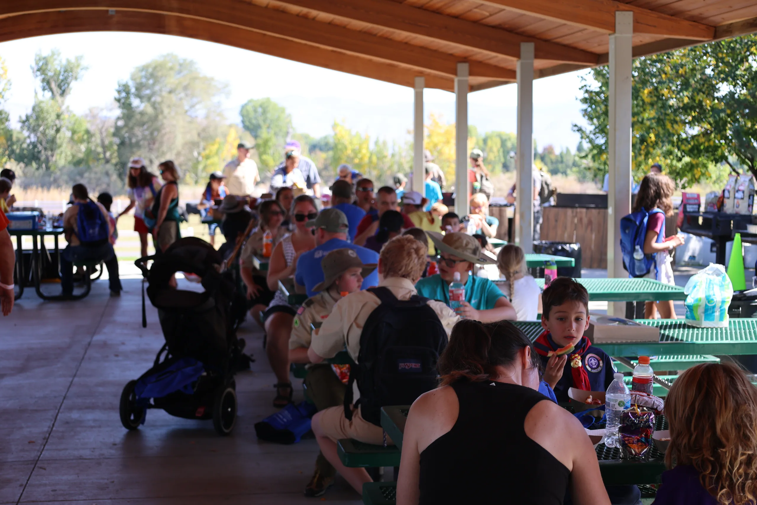 Scouts and their families having lunch in a park pavilion.